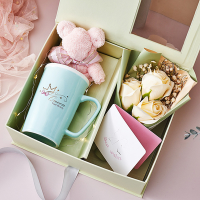 Une tasse en céramique créative, une serviette, un savon, un bouquet de cartes de vœux, des souvenirs.